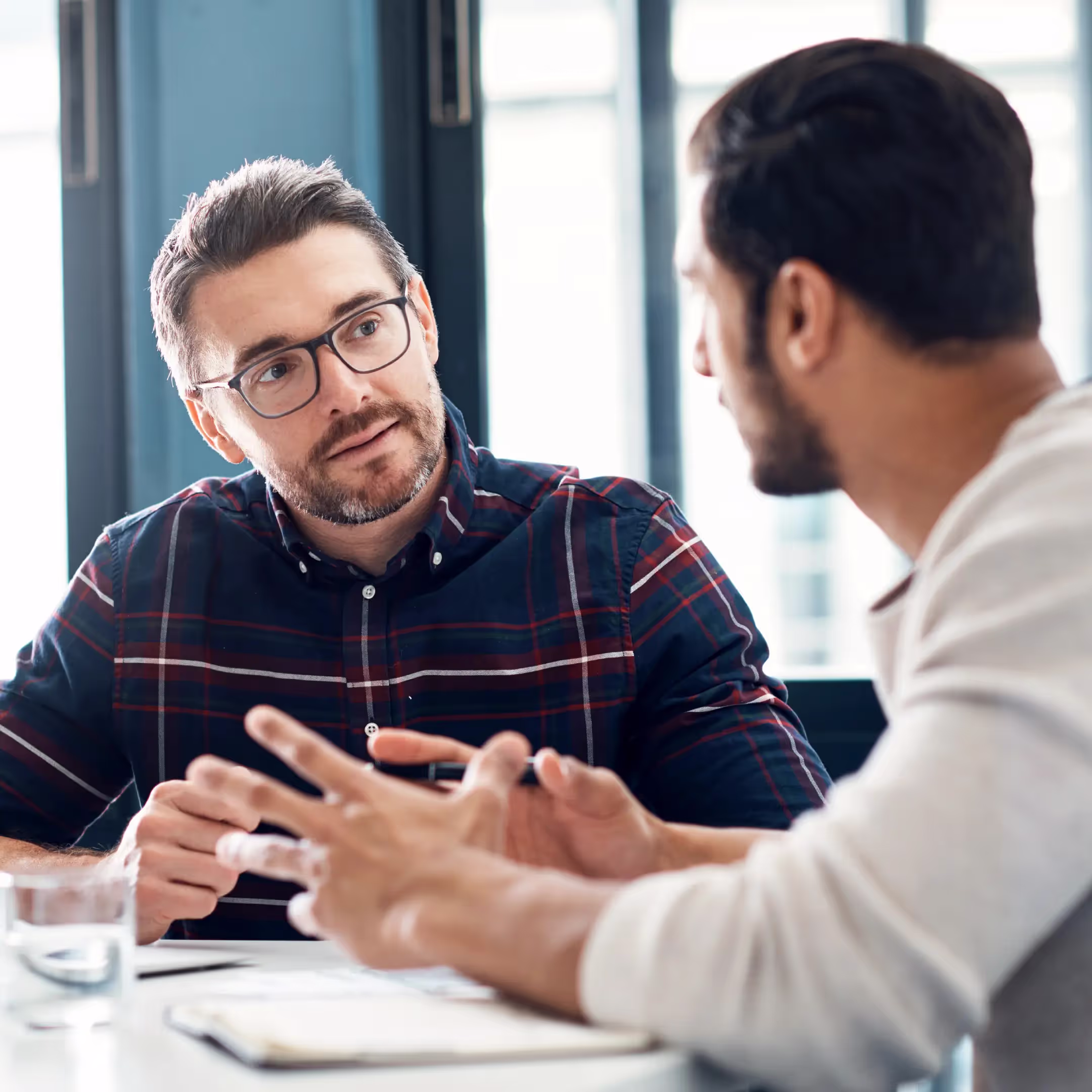 A supervisor and employee conducting a 1 on 1 meeting in an office setting.